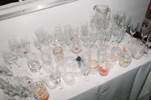 Various empty wine and cocktail glasses arranged on a white counter surface in an organized display pattern.
