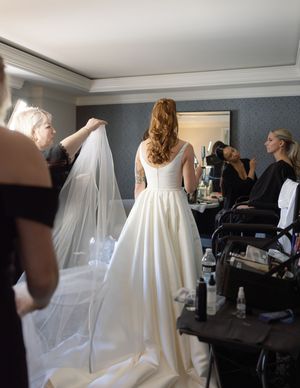 Behind-the-scenes moment of wedding preparation showing a flowing white dress and veil.
