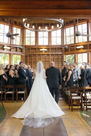A stunning wedding ceremony in a timber-framed chapel with natural light streaming through large windows.