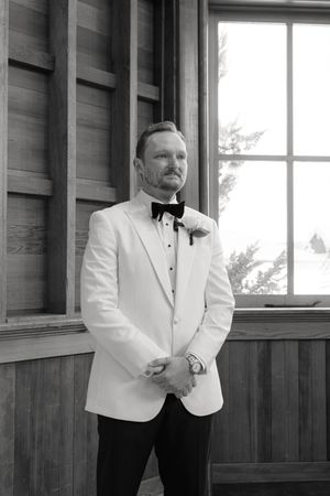 A stylish white tuxedo jacket and black bow tie ensemble captured in elegant black and white photography.