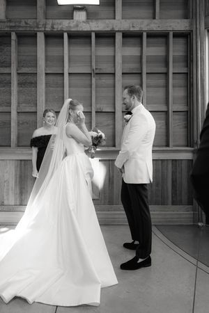 A couple exchanges vows during an intimate wedding ceremony in a rustic wooden venue.