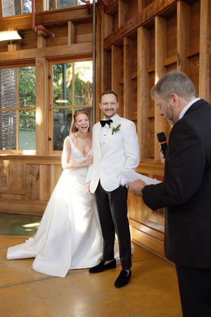 A couple shares a joyful moment during their wedding ceremony in a rustic wooden venue. Sunnyside conservatory in San Francisco wedding