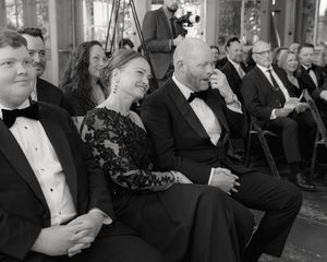 Wedding guests in formal attire enjoying a special moment during the ceremony.