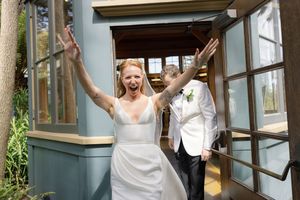 Wedding couple celebrating joyfully as they exit a building together on their special day.