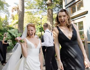 Wedding attendees share joyful moments outdoors near palm trees during a celebration.