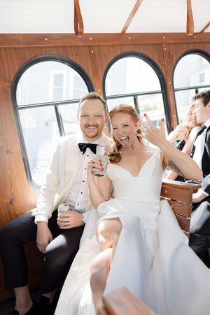 Newlyweds share a joyful moment while riding in a vintage trolley after their ceremony.