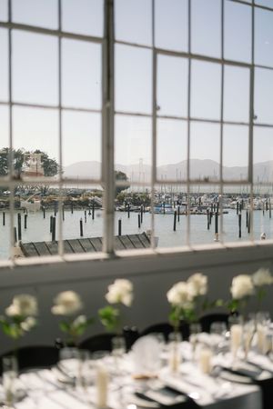 Modern reception venue with large windows overlooking a marina and mountains.