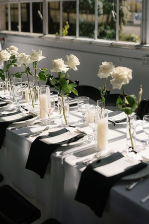 Elegant wedding table setting with white roses and place settings in natural light.