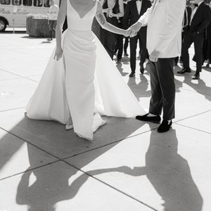 Black and white editorial photo showing the elegant draping of a wedding gown and formal shoes on a tiled outdoor dance floor. San Francisco