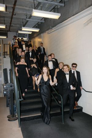 Wedding party in formal attire descending industrial staircase in black and white theme.