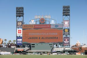 Oracle Park stadium scoreboard displays wedding congratulations message against blue sky background.