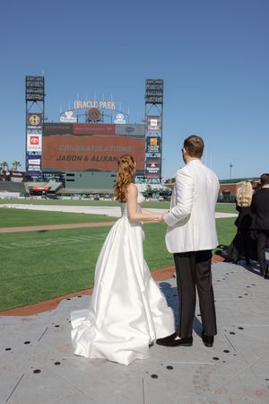A wedding couple stands at Oracle Park baseball stadium in San Francisco as five sequential photos show them posing on the field.