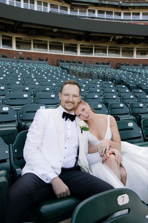 Newlyweds relaxing in empty stadium seats during their wedding photoshoot.