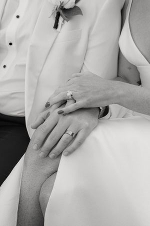 Close-up of hands resting on a white dress showing a wedding ring.