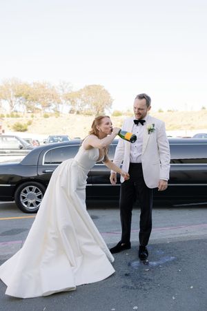 A joyful wedding moment captured in a parking lot with a limousine in the background.