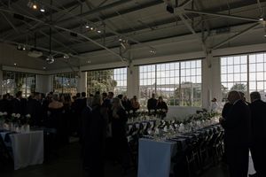 A spacious industrial event space with dark tablescapes and dramatic lighting for a wedding reception.