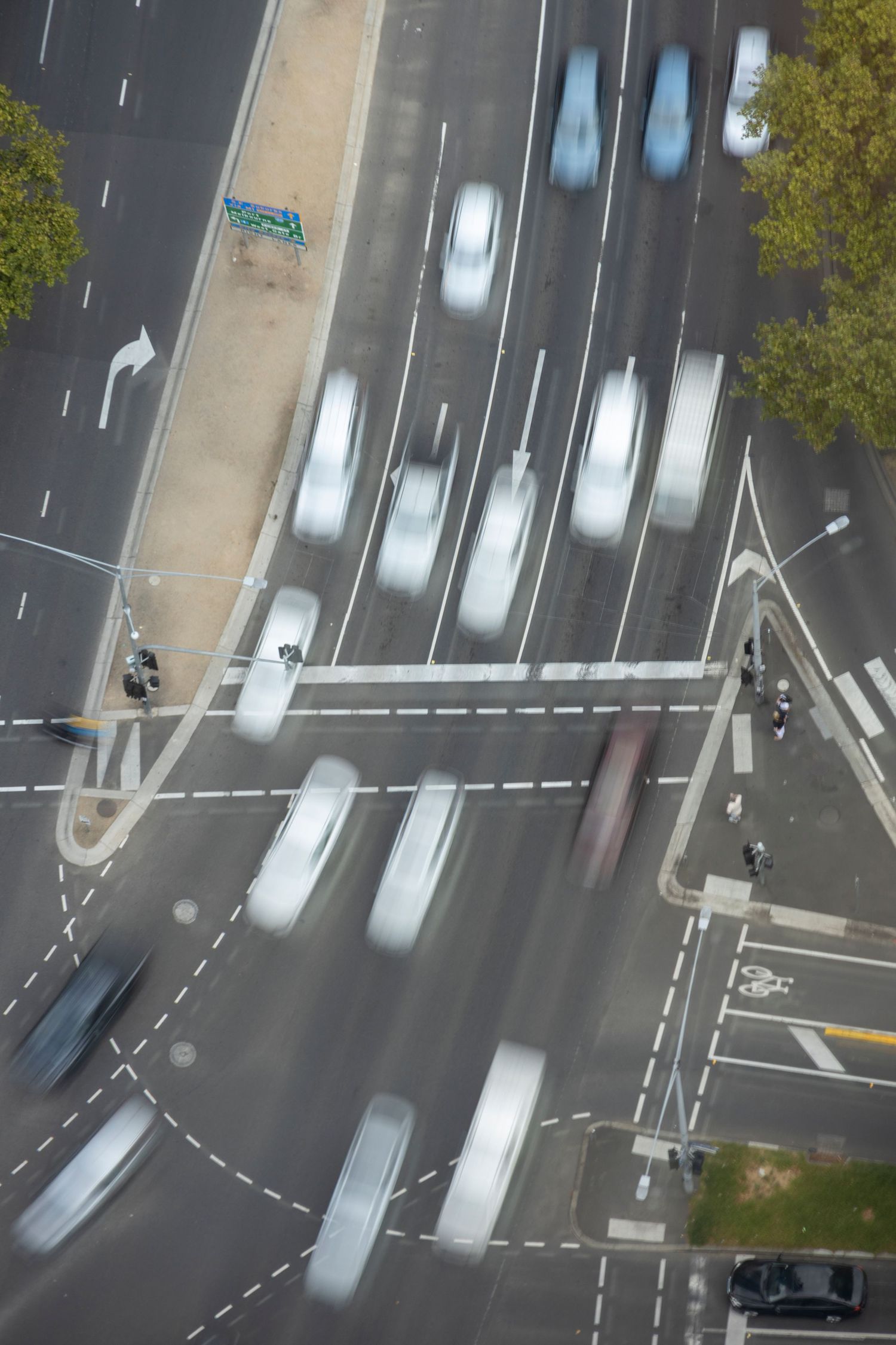 Long-exposure shot of a busy city intersection with streaks of traffic and blurred motion.