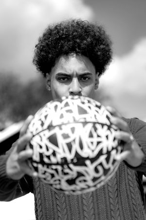 Black and white portrait with graffiti-styled ball covered in urban art lettering in the foreground.