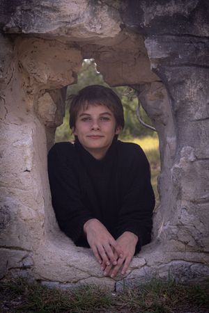 A child peeks through stone wall openings in a creative photo series showing different playful poses.