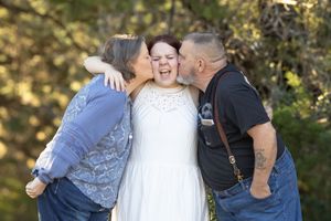 A joyful wedding party poses together outdoors with playful expressions and laughter.