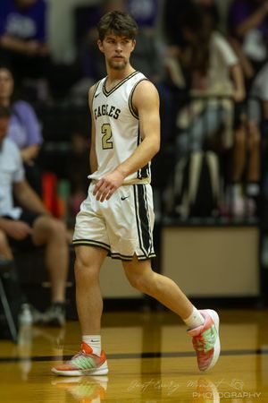 Basketball player in white Eagles jersey number 2 dribbles on court wearing colorful sneakers during game.