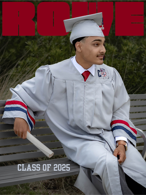 A graduate in white cap and gown with red and navy accents sits casually on a bench in an outdoor setting.