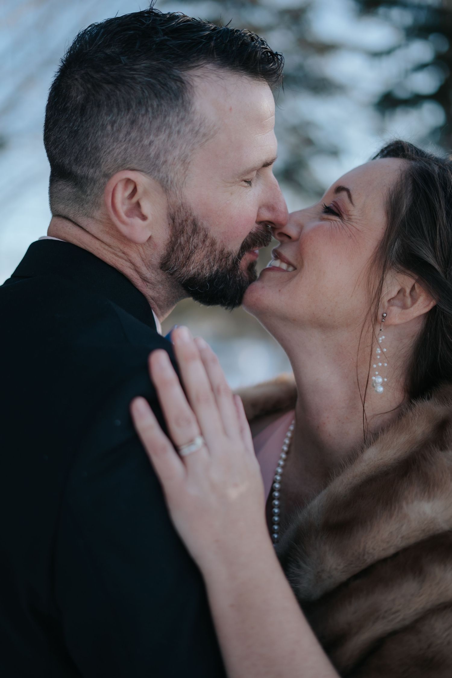 Intimate winter wedding portrait of couple embracing and smiling.