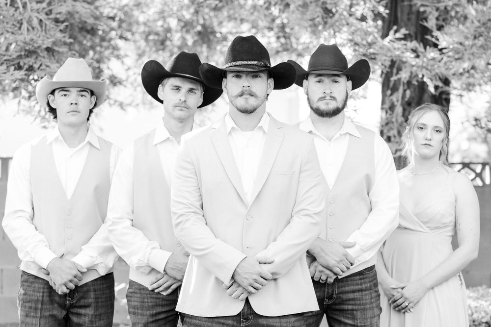 Wedding party members in western attire line up for a formal group photo.