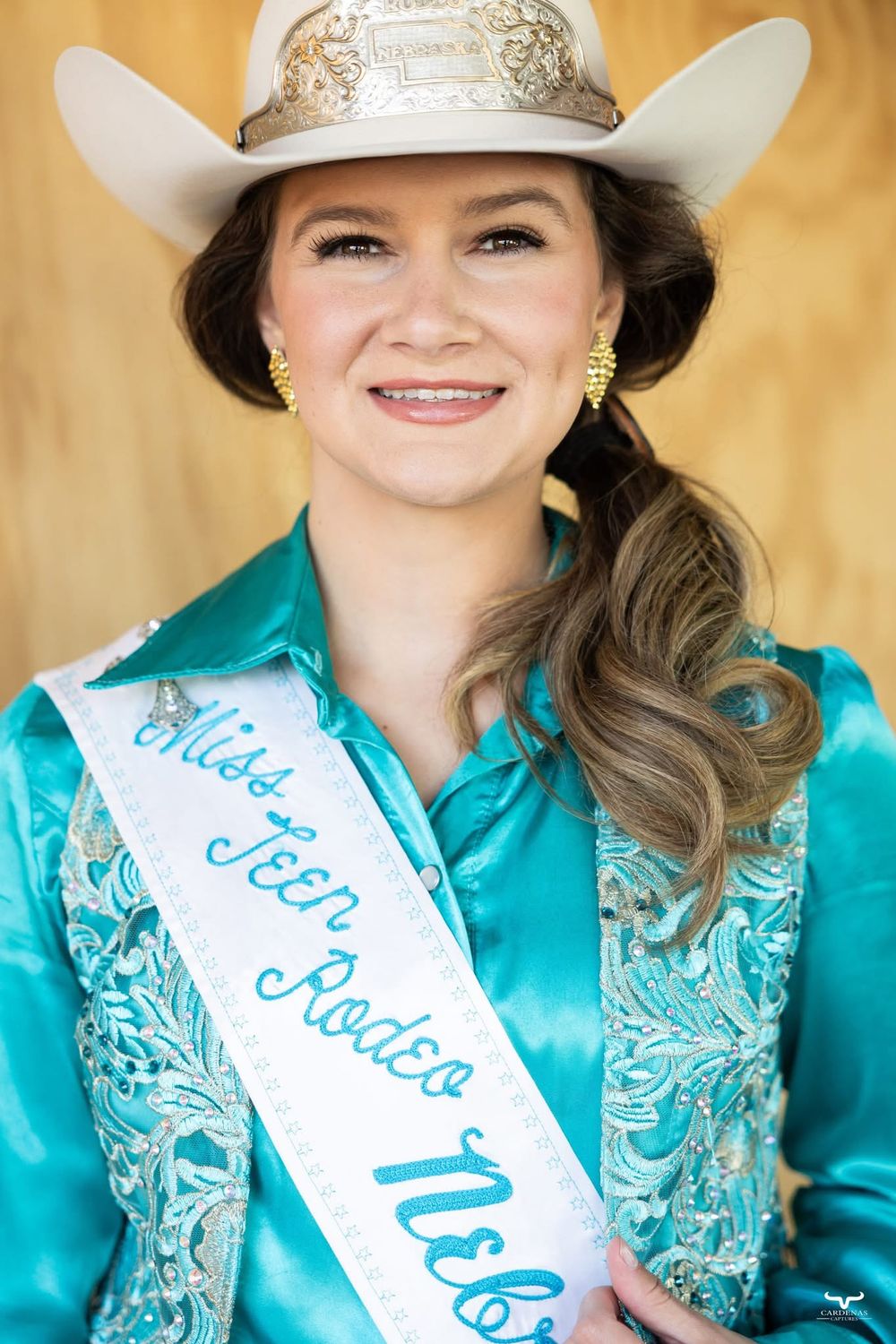 Rodeo queen wearing turquoise embellished outfit and decorative sash with crown. Pro Rodeo PRCA Rodeo Photographer Dakota Cardenas