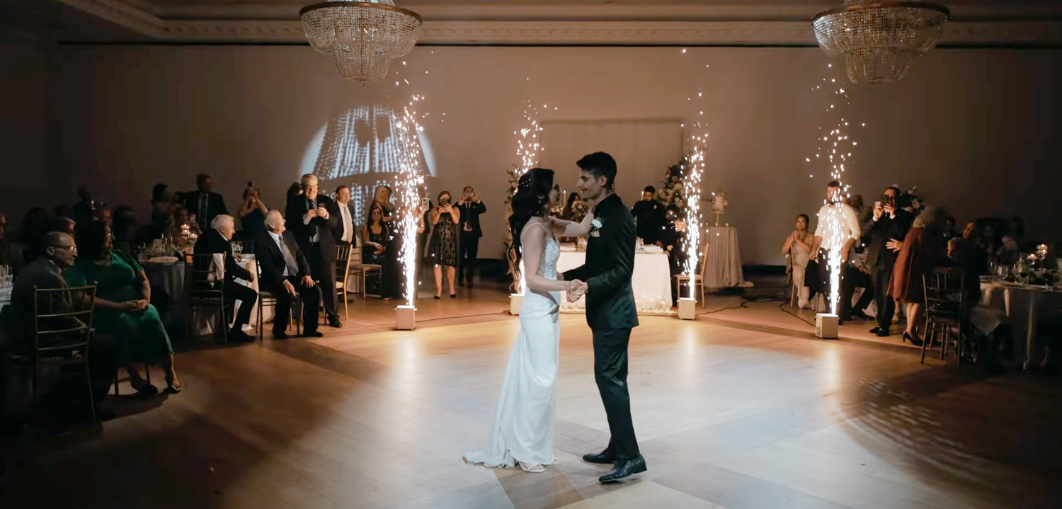 Couple shares romantic moment under draped fabric wedding arch at outdoor ceremony.