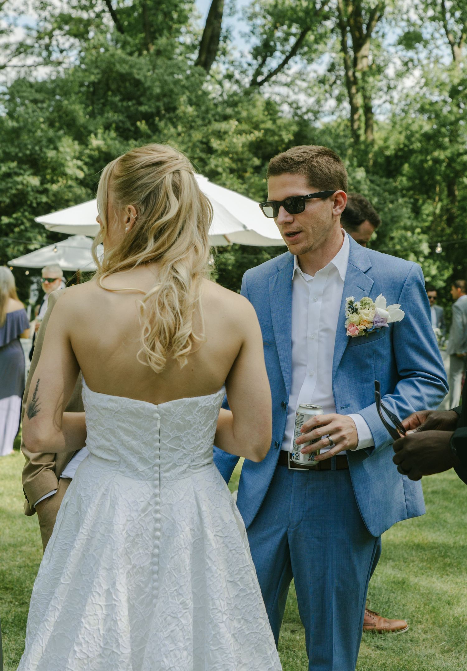 A sunny outdoor wedding reception with elegant white decor and floral arrangements.