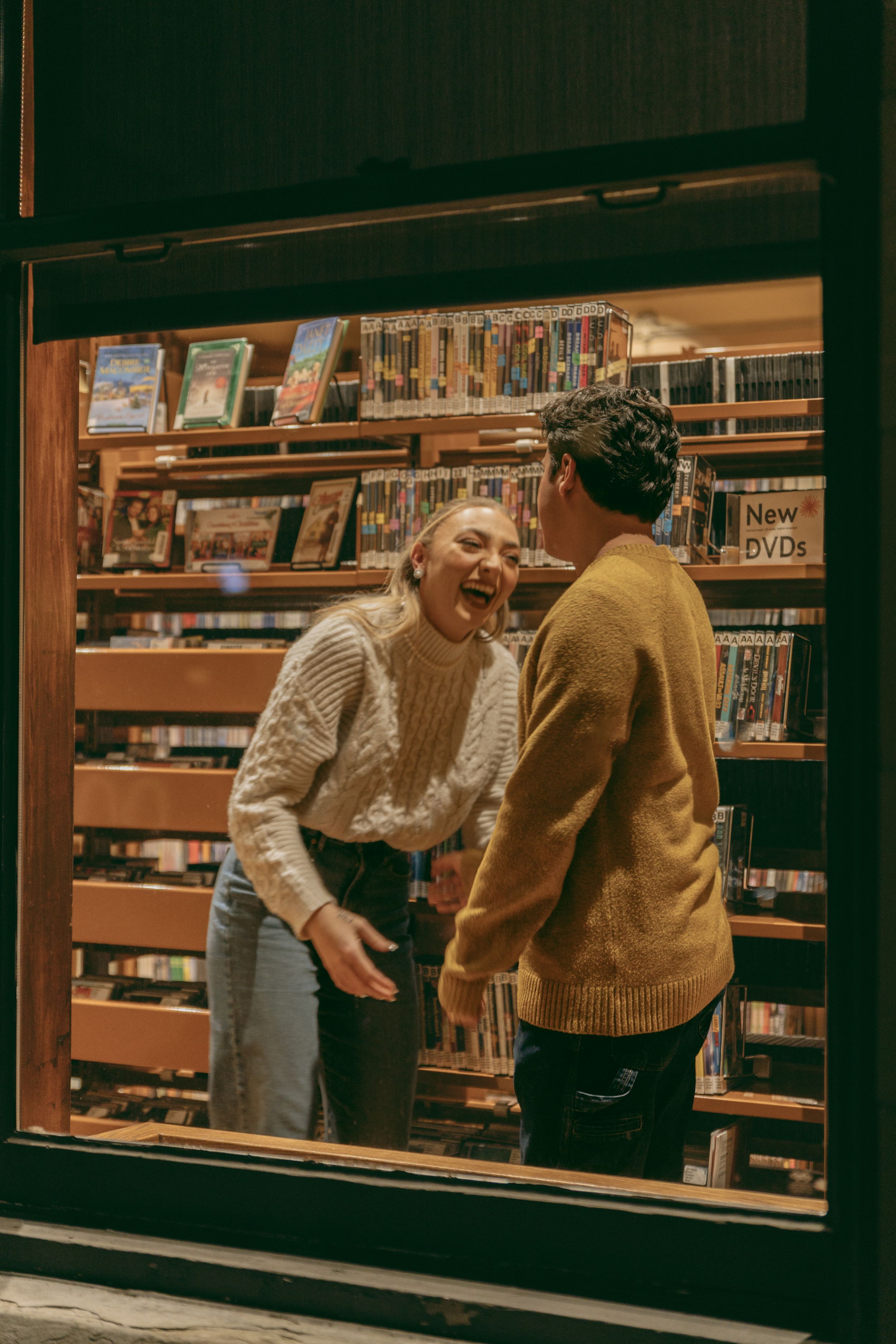 Joyful moment shared between two people in a library media section.
