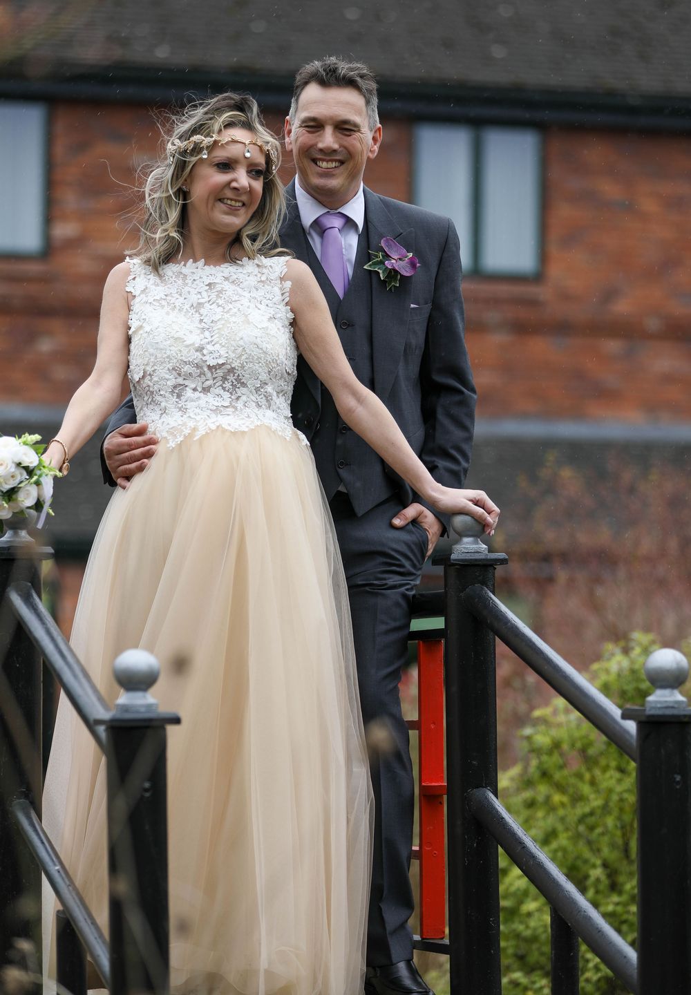 Joyful bride in champagne tulle gown laughing with groom on rustic stairs.