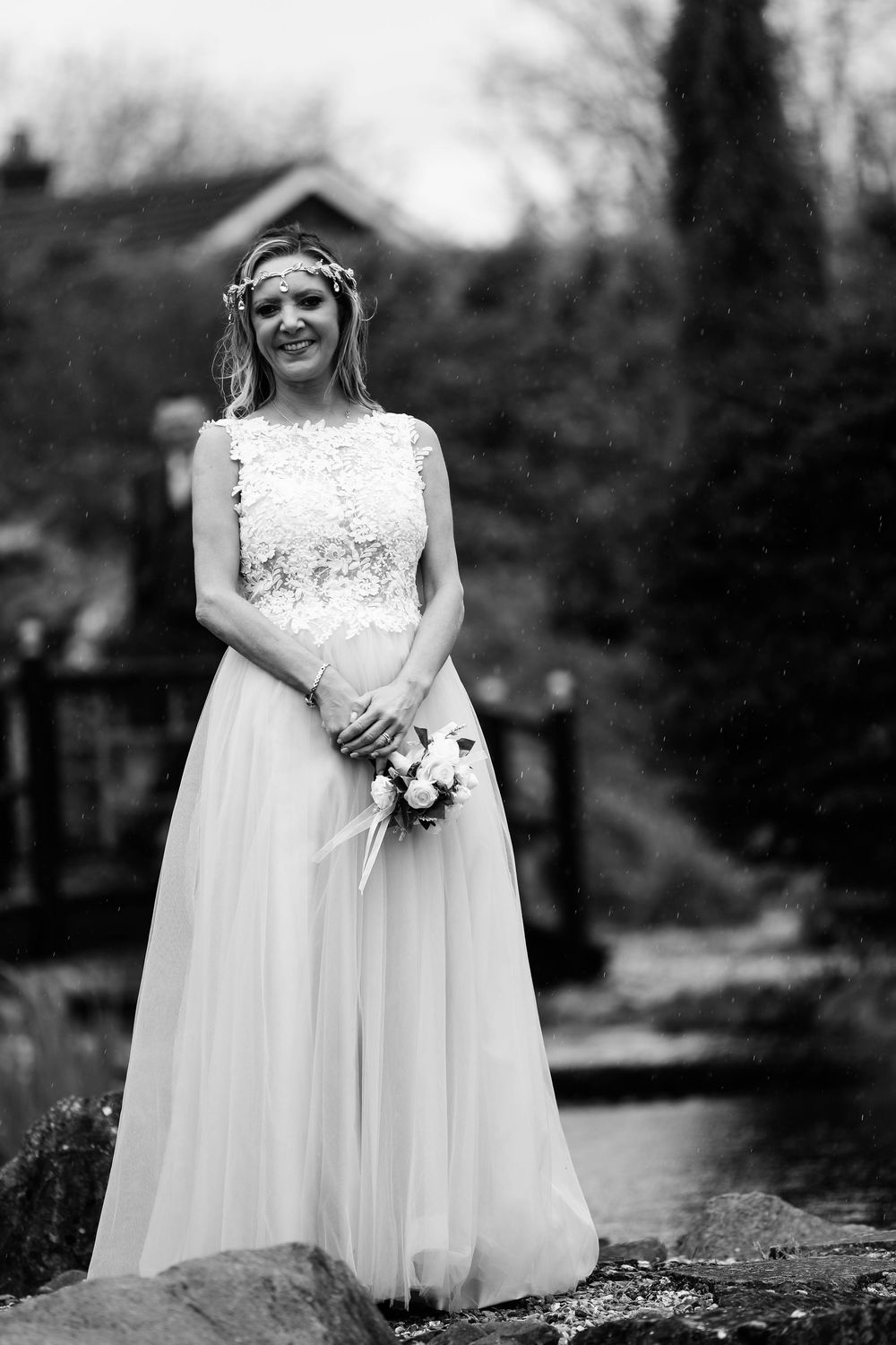 Black and white portrait of radiant bride in lace and tulle gown holding white bouquet.