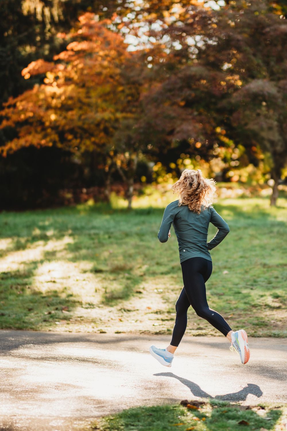 Motion sequence of a jogger running on a path surrounded by autumn trees with orange and golden foliage.