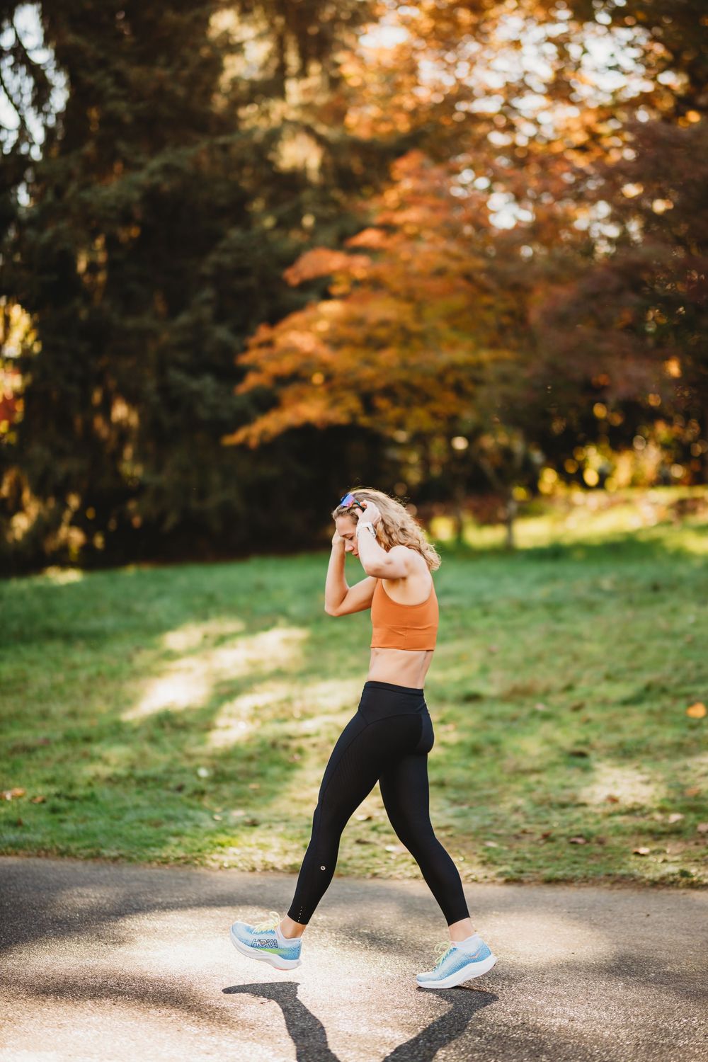 Athletic person practicing kickboxing moves outdoors on a paved trail surrounded by fall foliage.