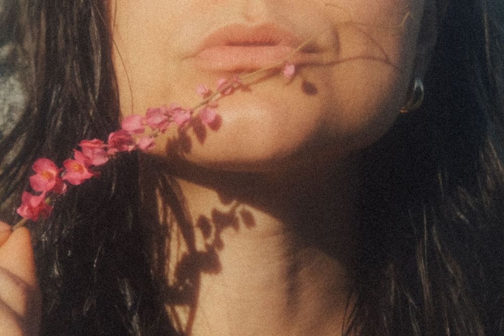 A collage of closeup portraits with pink flowers and dark hair against a black background.