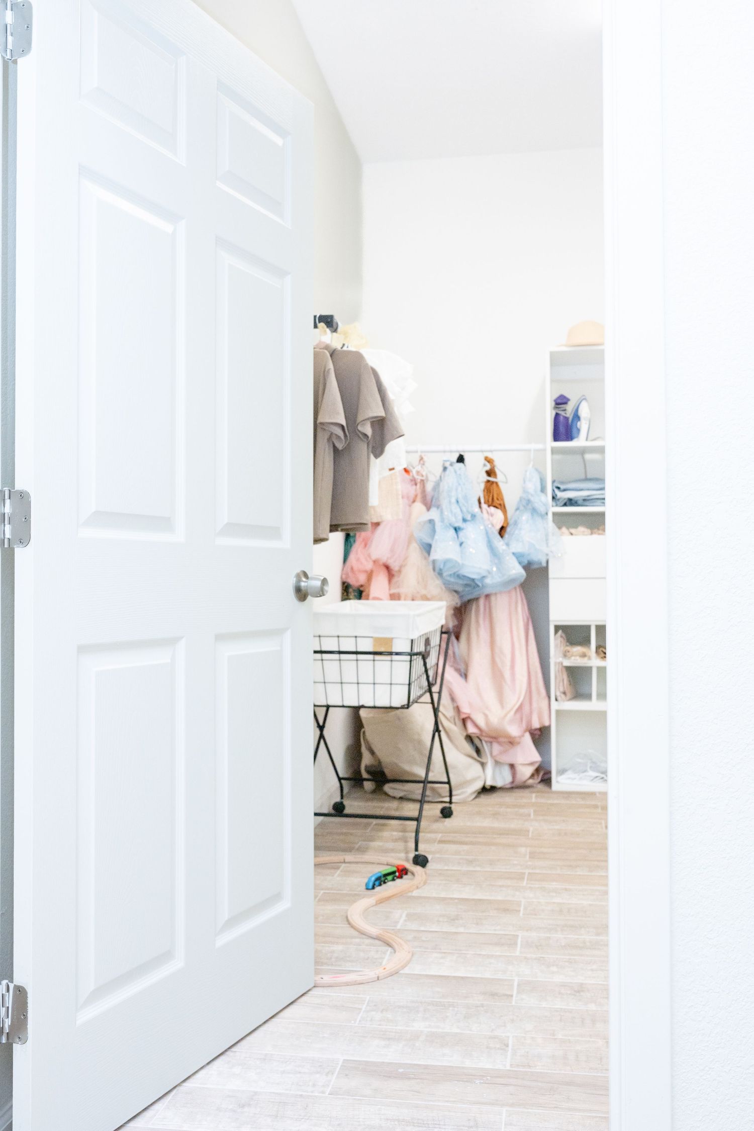 Bright and airy retail space with white shelving and clothing displays against wooden flooring.