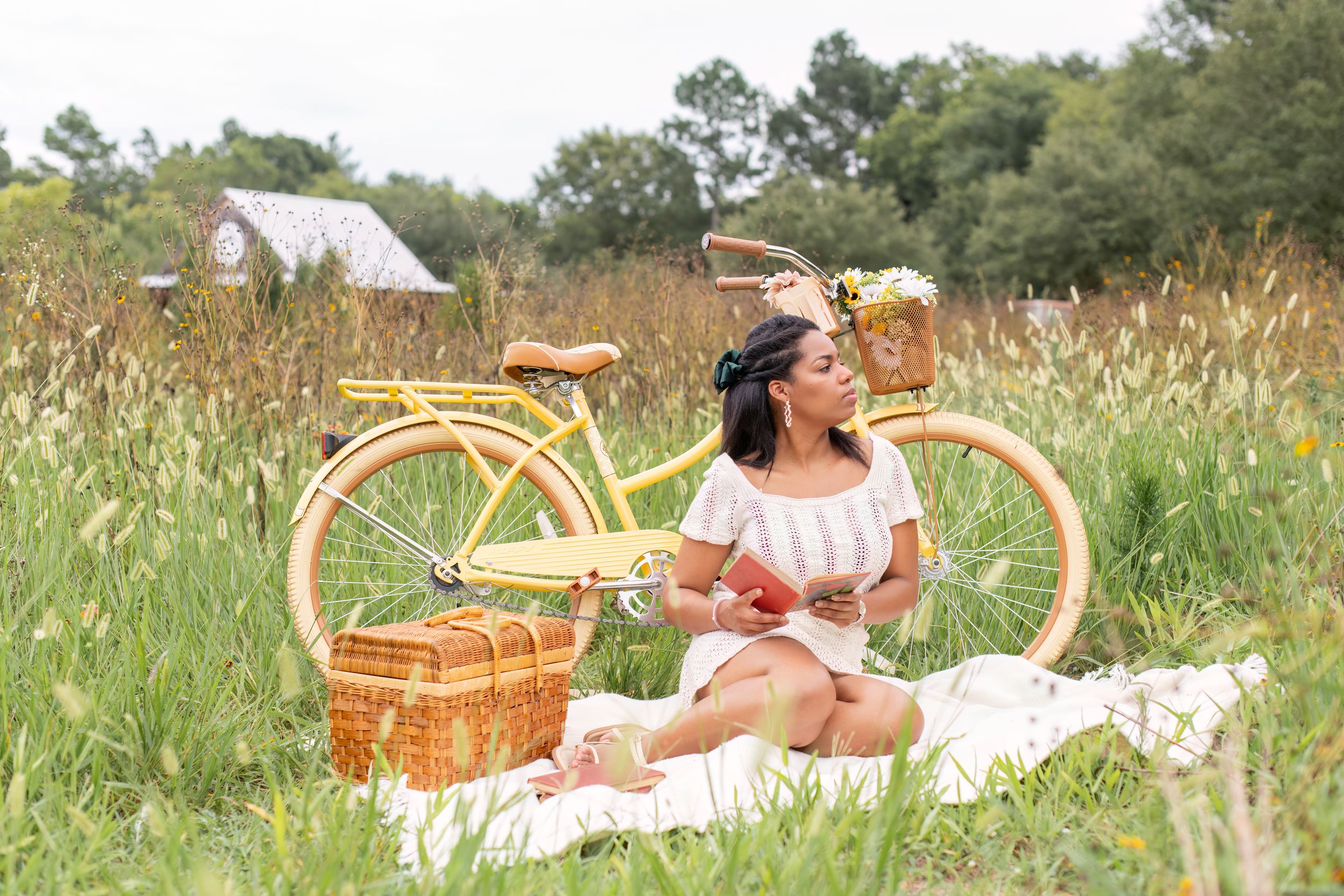 Girl in field at Cedar Ridge Tree Farm with Christmas trees and yellow bike.