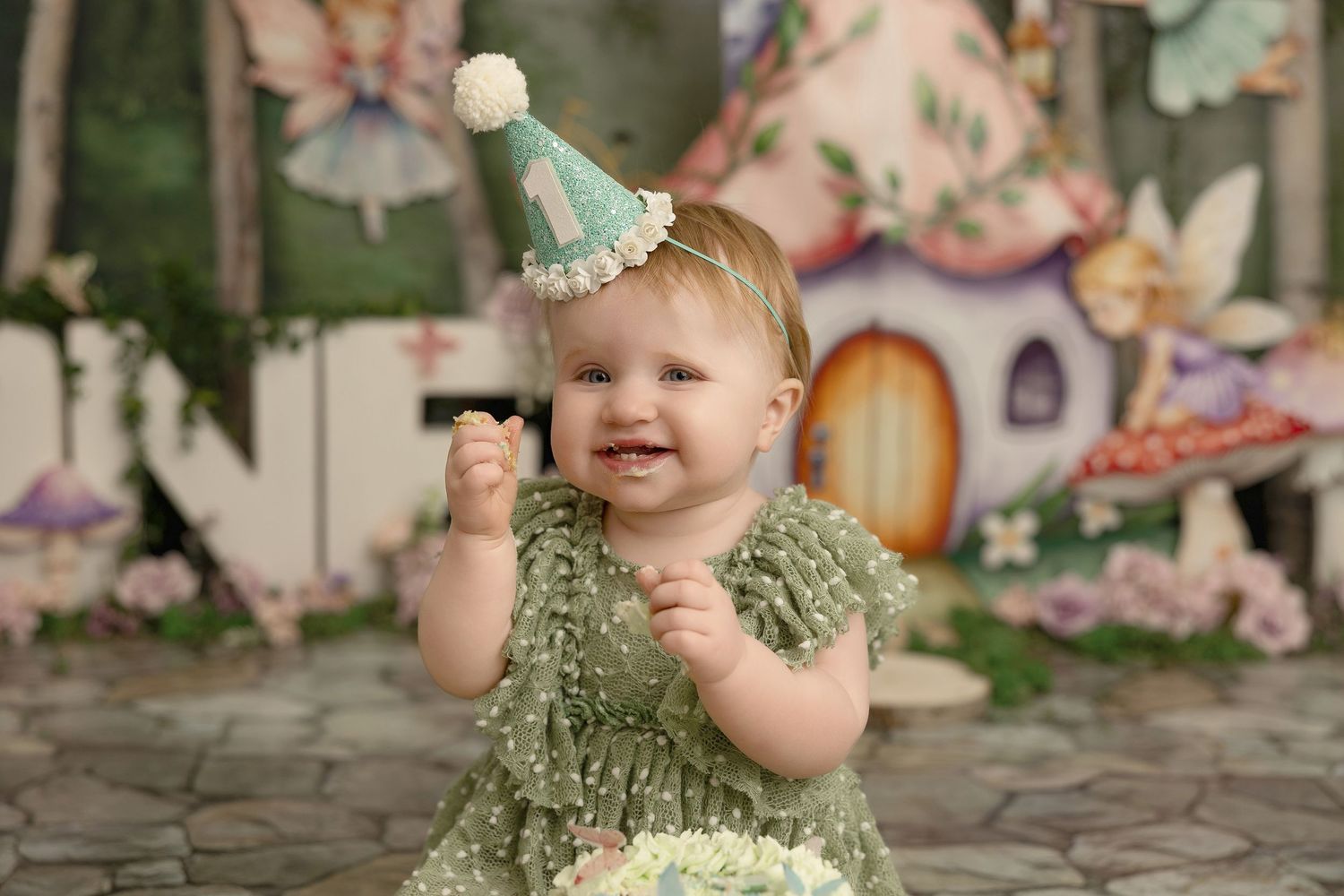 A little one in olive green lace romper sits on stone steps with a whimsical autumn background.
