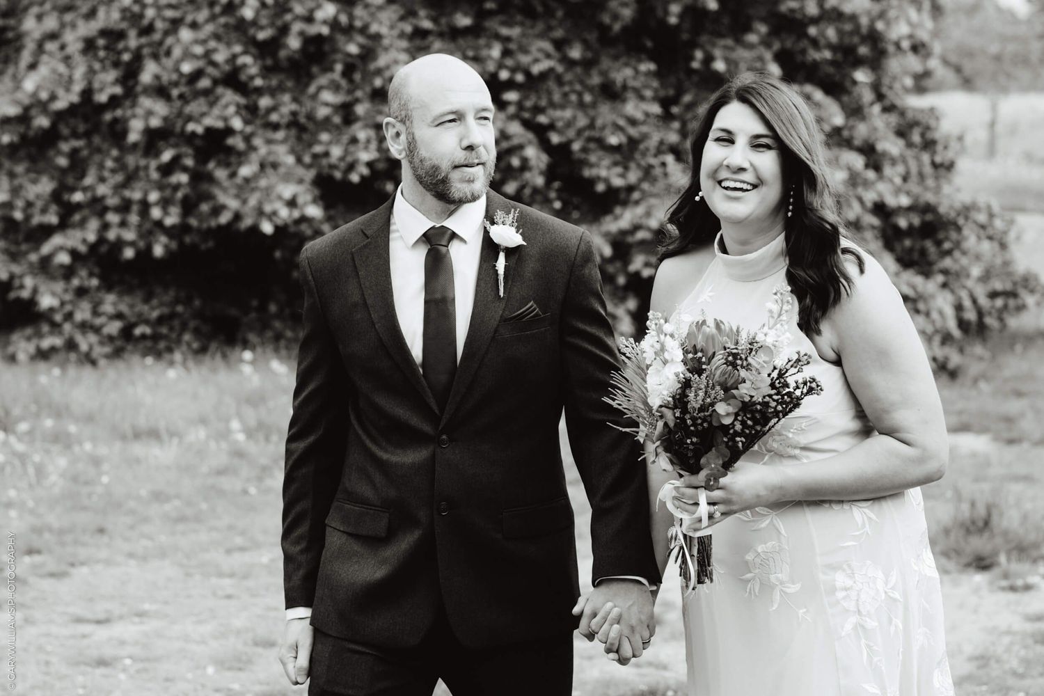 A romantic black and white wedding photo shows the newlyweds outdoors with blurred trees in the background.