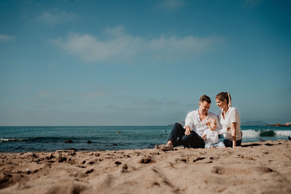 Familia sentada en la arena de Mazatlán, mar y cielo de fondo (destination photographer Mazatlán)