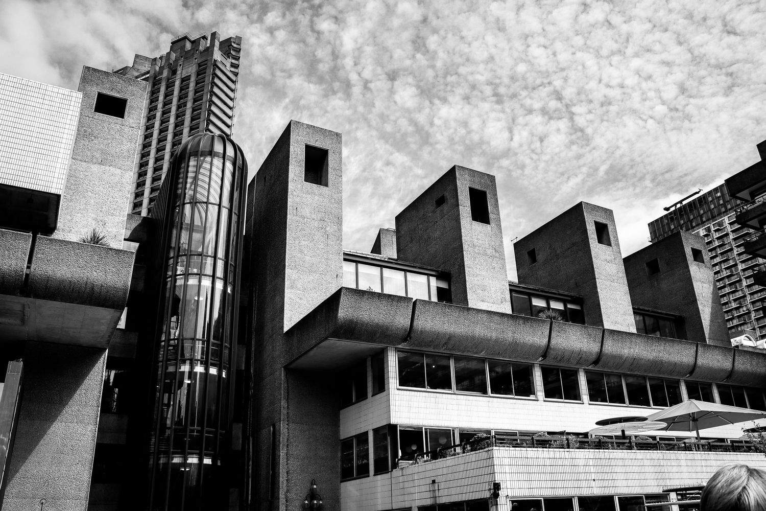 The Barbican. City of London. Brutalist concrete building with angular towers and textured surfaces under a cloudy sky.