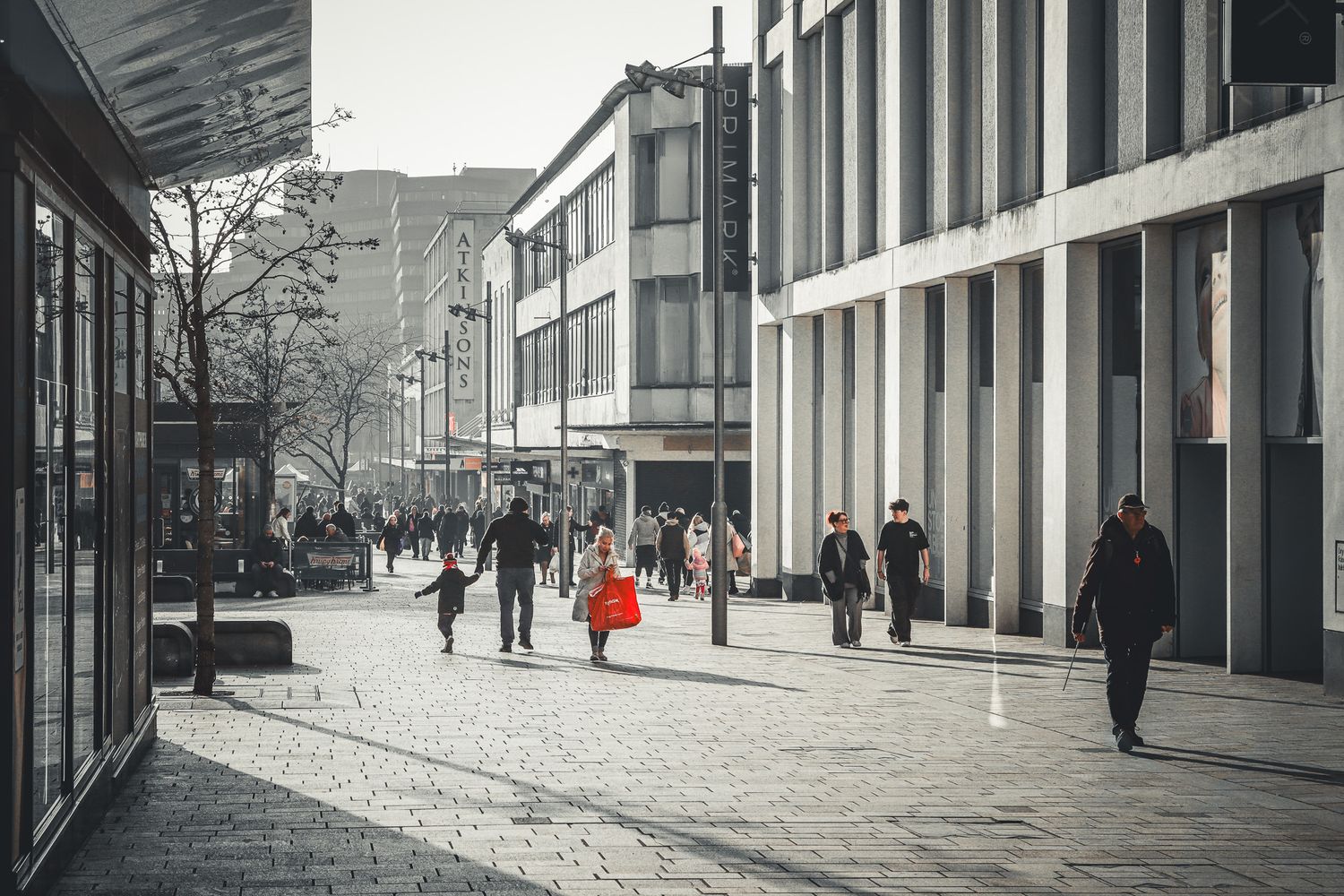 The Moor, Sheffield. Shoppers walking through a city street lined with mid-century concrete offices.