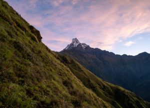 Dramatic sunset sky over mountain peaks with pink and purple hues illuminating the landscape.