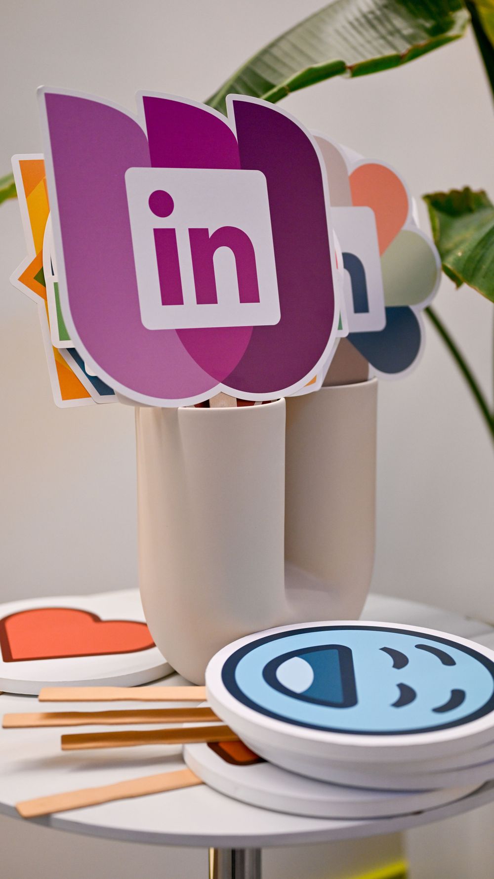 Colorful social media logo photo booth props including LinkedIn displayed in a white cup on a table.