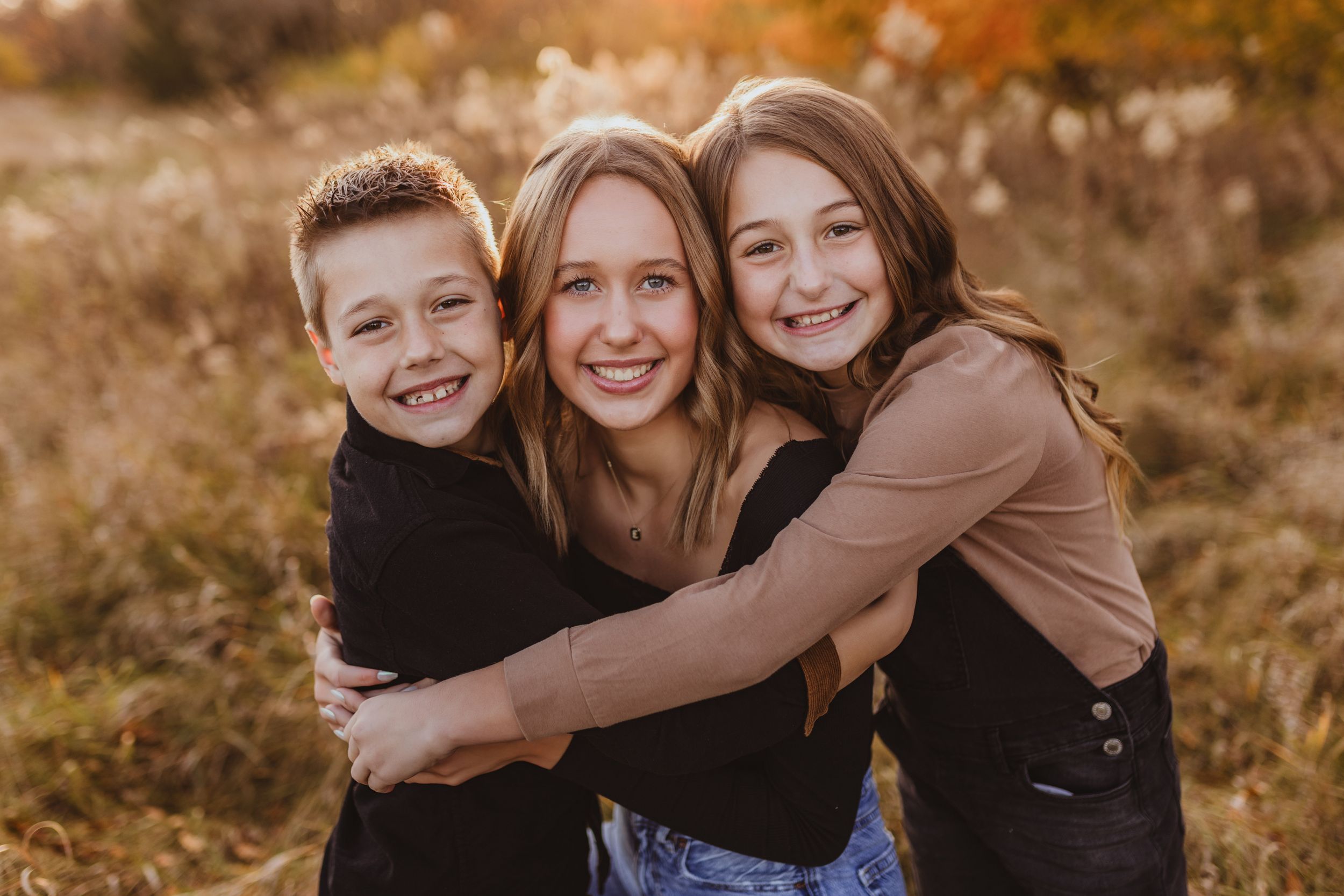Candid family photo shoot with natural laughter in a fall field setting.