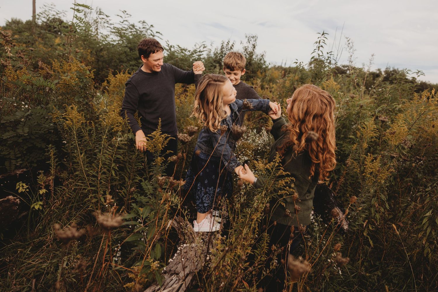 Candid family photo shoot with natural laughter in a fall field setting.