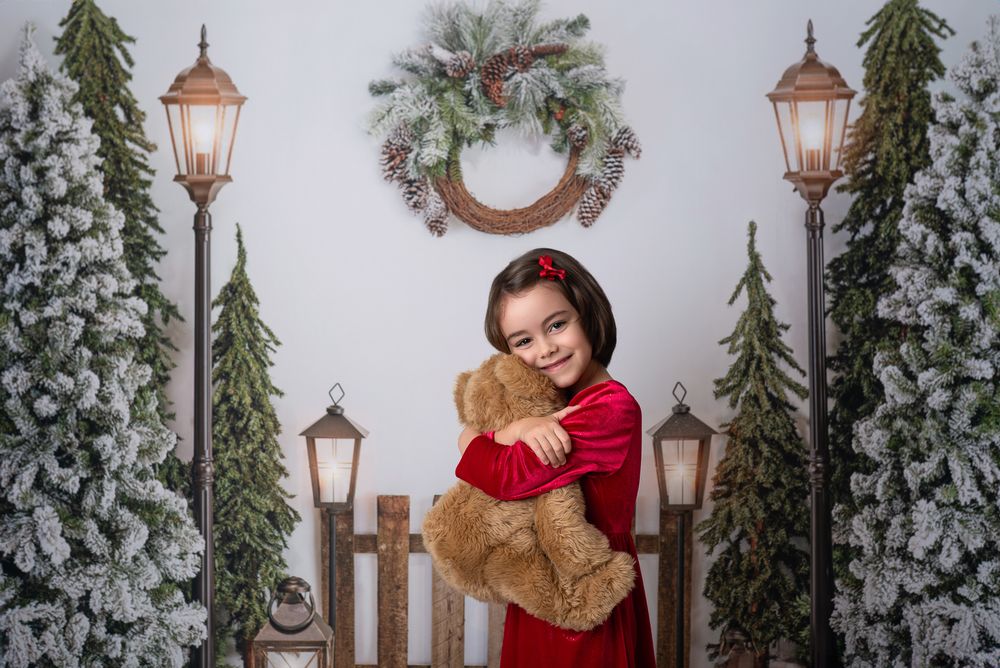 A winter scene with decorative lamp posts, evergreen trees, and holiday garland creates a festive outdoor setting.