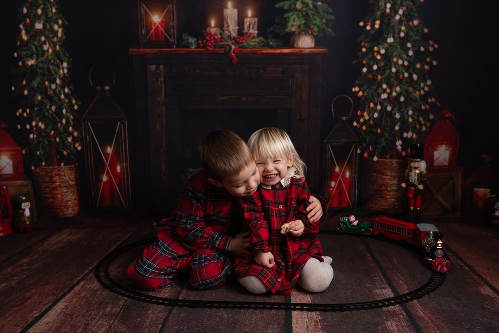 Dark holiday scene with decorated Christmas trees, glowing lights, and festive red and white decor against a rustic backdrop.